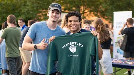 Two students holding Chi Theta Pi sweatshirt